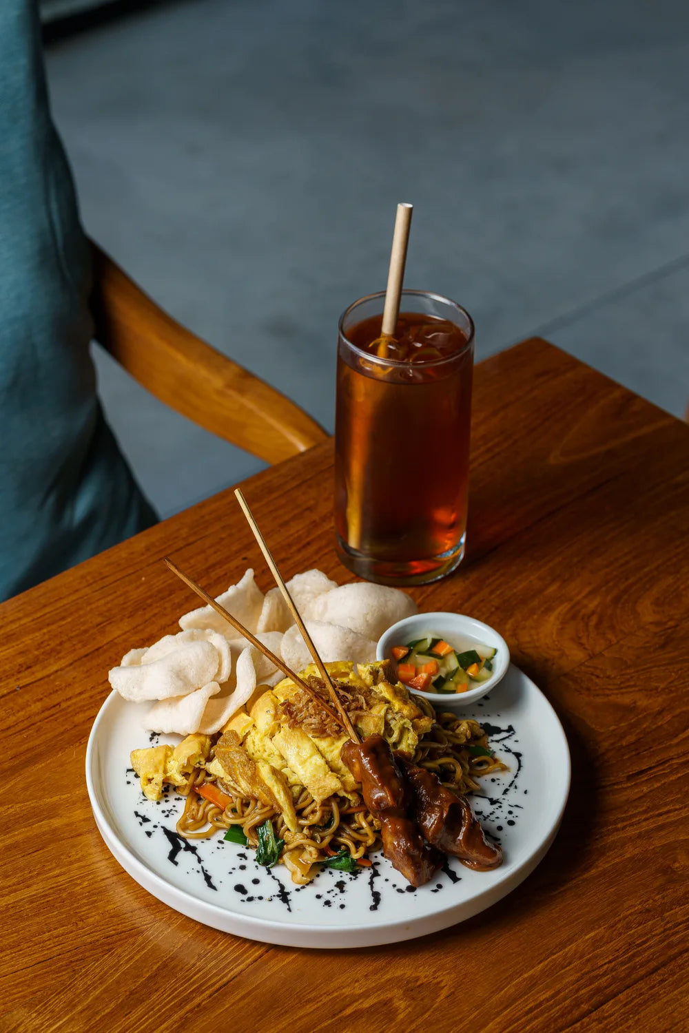 Noodles topped with egg, served with satay skewers and crackers.