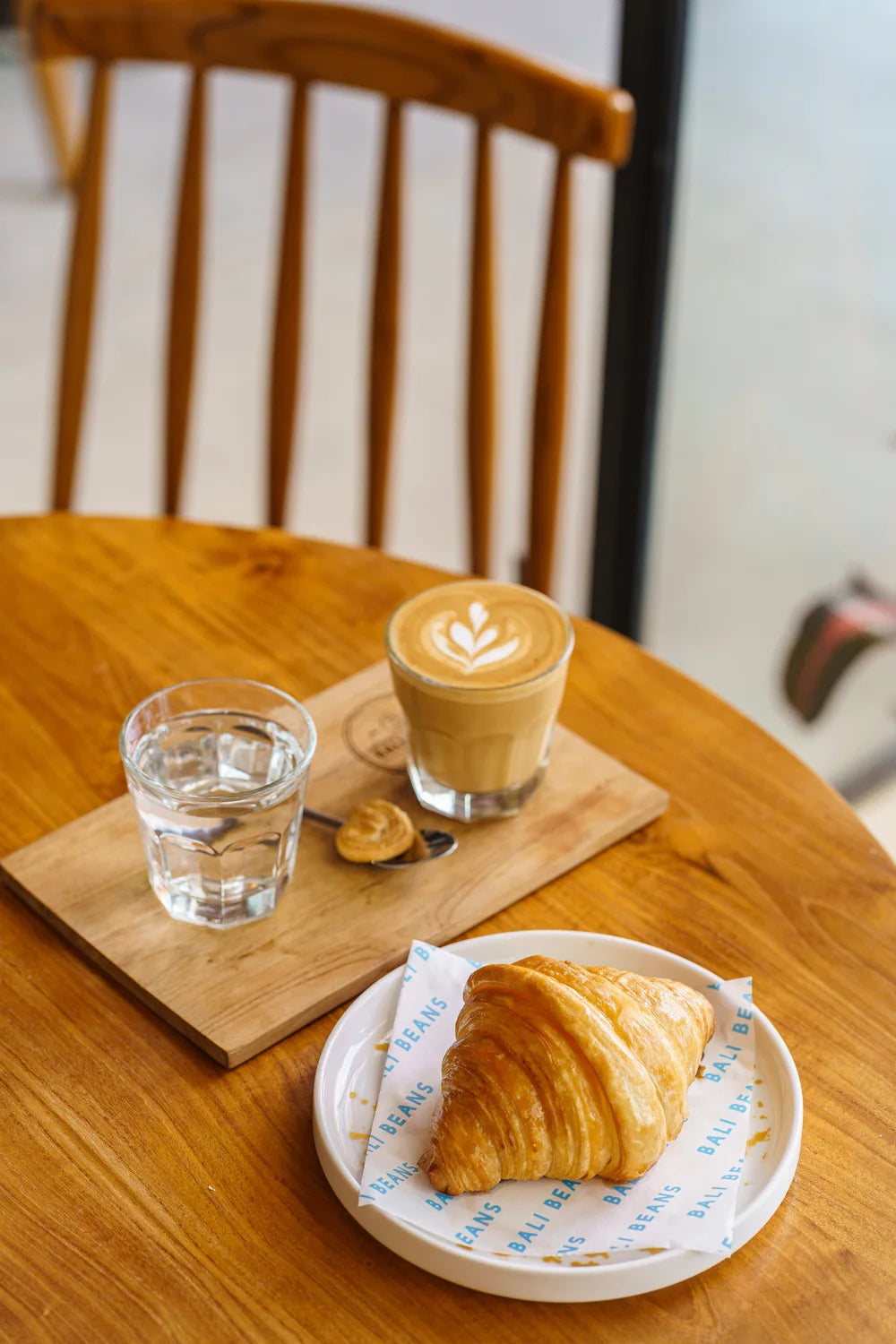 A cup of coffee with latte art, alongside a golden croissant.