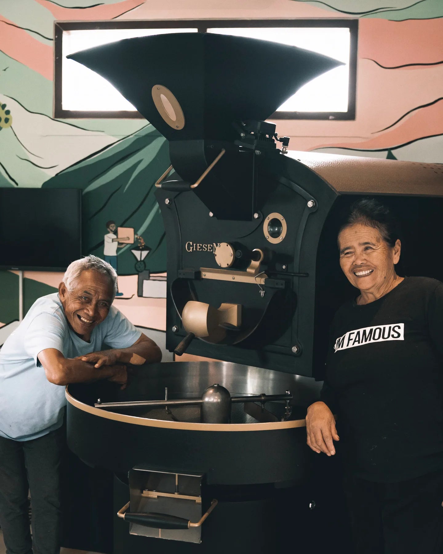 Two people beside a coffee roaster